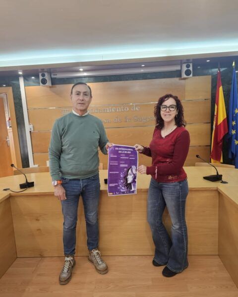 Dos personas sosteniendo un cartel del Día Internacional de la Mujer en un ayuntamiento.