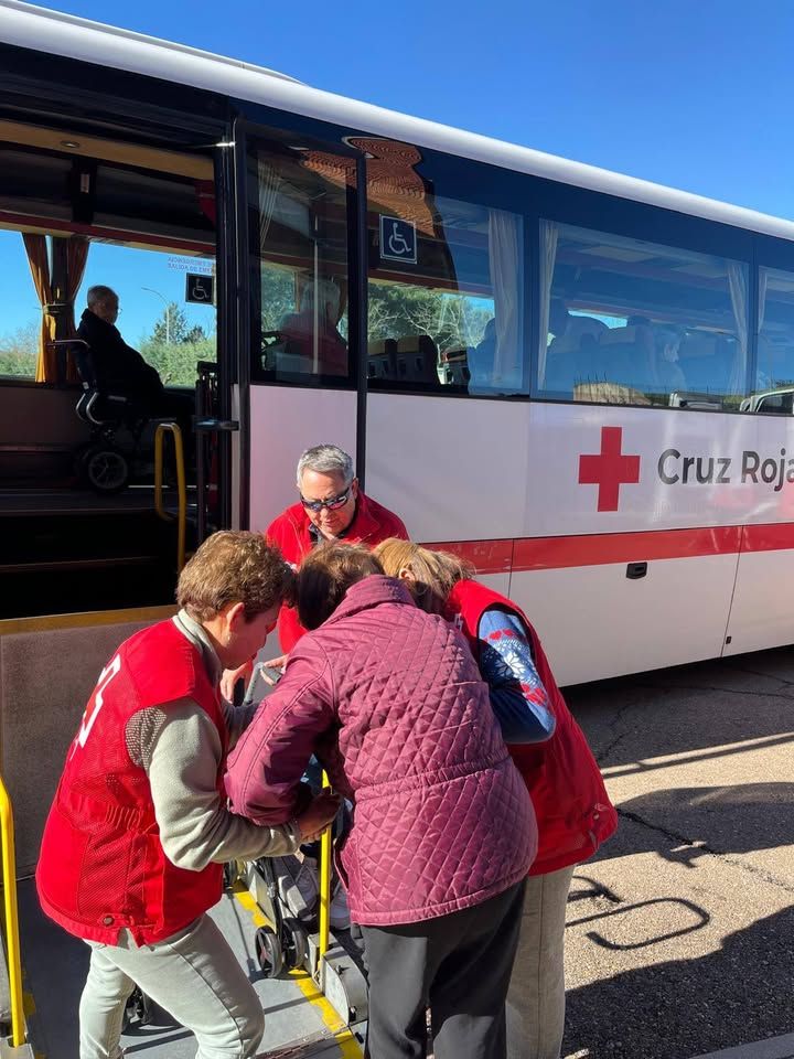 Voluntarios de Cruz Roja ayudan a votantes con movilidad reducida a subir a un autobús adaptado.