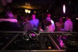 Vista de un local de ocio nocturno con personas bailando y una mesa de DJ
