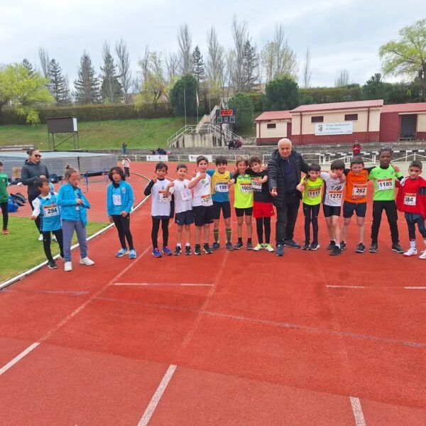 Grupo de jóvenes atletas en pista de atletismo durante evento escolar