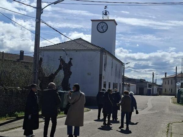 Grupo de personas caminando hacia un edificio con reloj en Fuentes de Oñoro