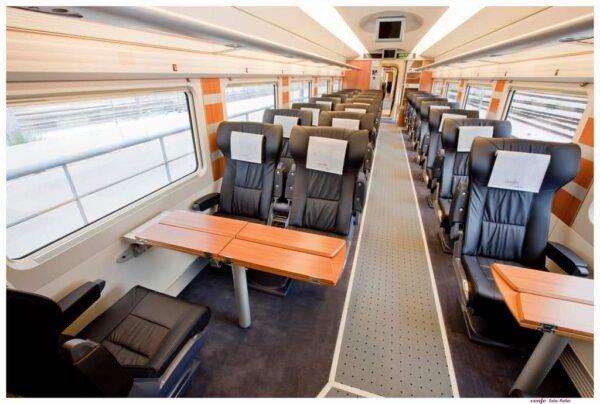Interior de un tren con asientos cómodos y mesas