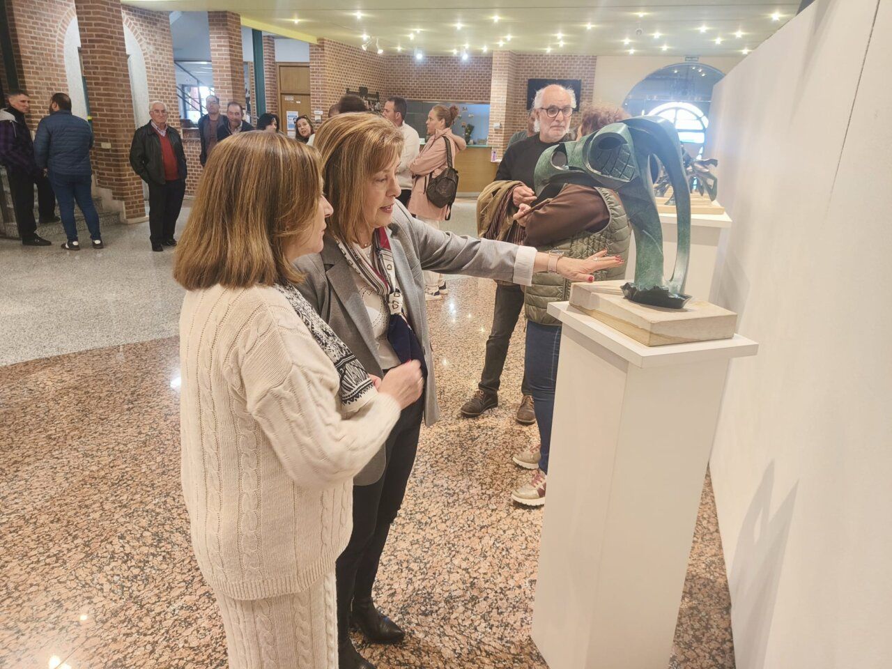 Dos mujeres observando una escultura en una exposición de arte