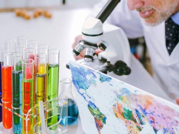 Científico observando a través de un microscopio con tubos de ensayo coloridos