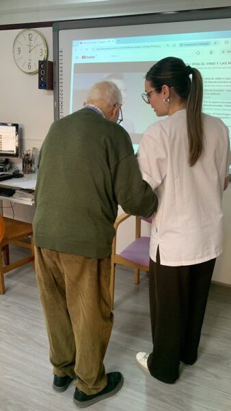 Estudiante ayuda a un anciano en una actividad educativa