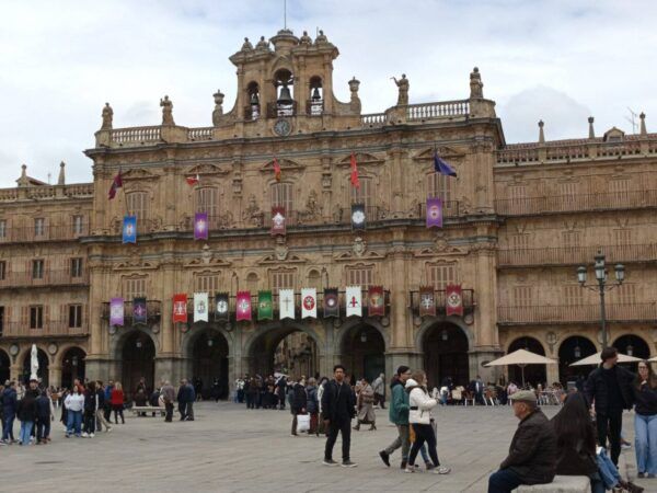 Vista de la Plaza Mayor de Salamanca durante la Semana Santa con gente y banderas.