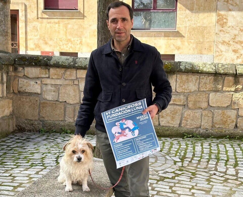 Hombre sosteniendo un cartel del VI Canicross Fundación Luna con un perro