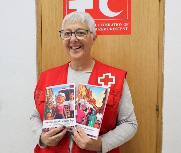 Mercedes, voluntaria de Cruz Roja, sonríe con libros en las manos