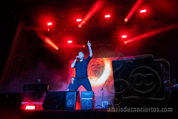 Beret actuando en un concierto con luces rojas y fondo visual
