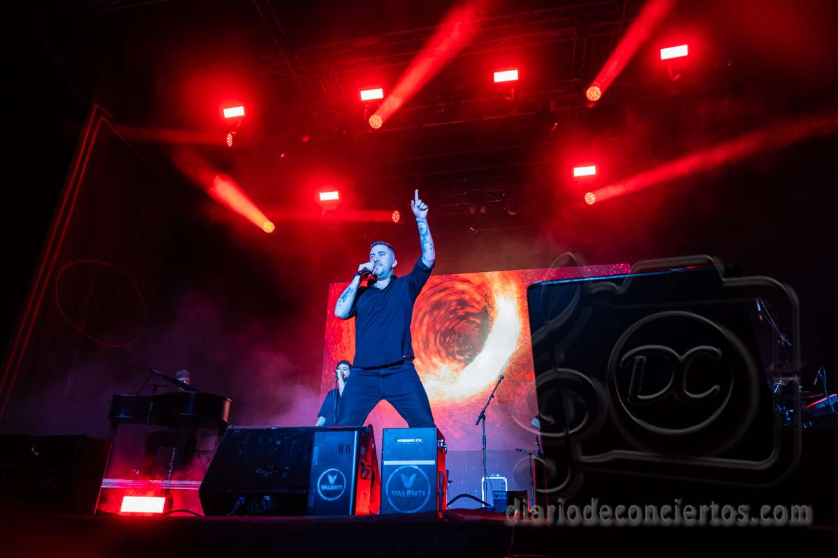 Beret actuando en un concierto con luces rojas y fondo visual