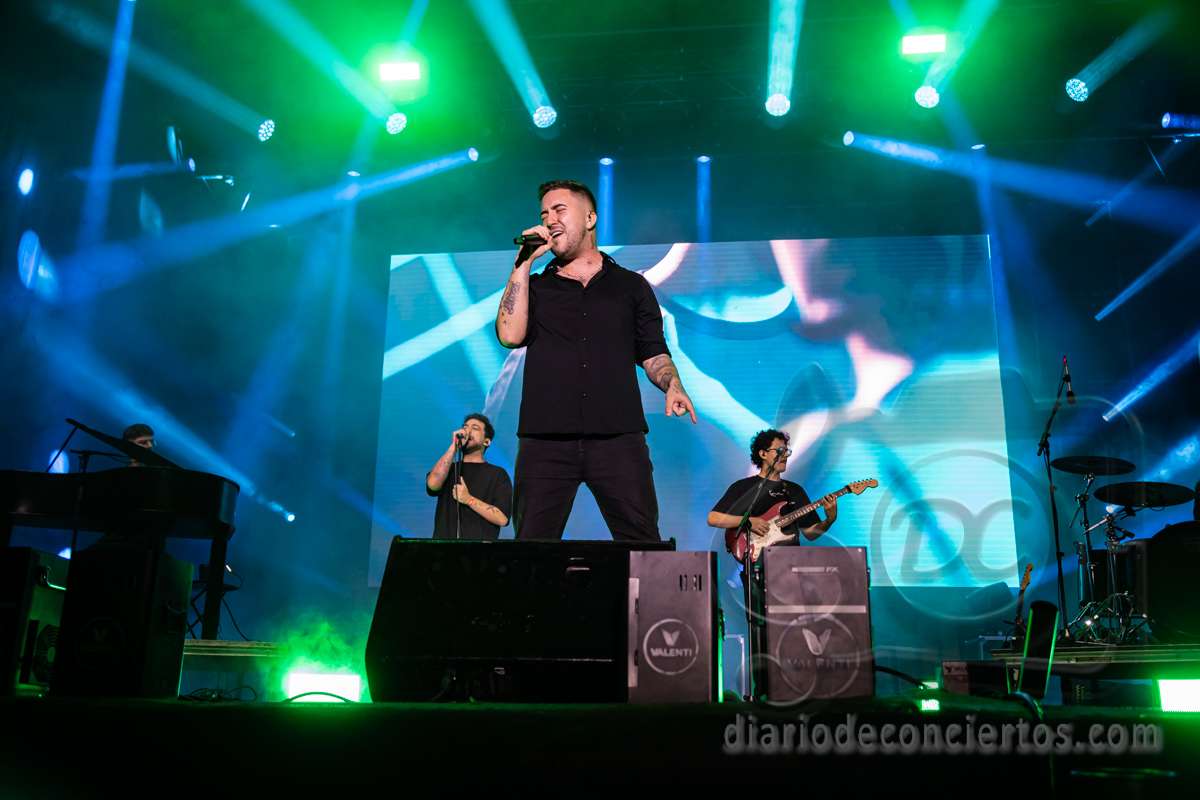 Beret actuando en un concierto con luces y músicos de fondo