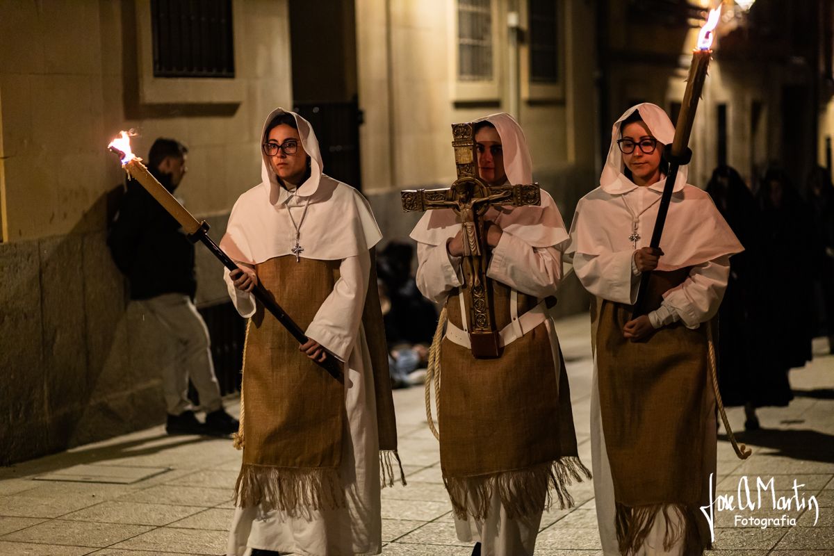 Tres mujeres con túnicas y antorchas en un acto religioso