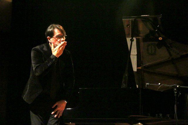 Músico en el escenario junto a un piano en un espectáculo de tango.
