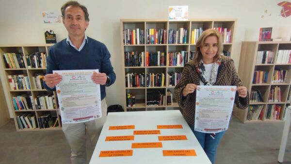 Dos personas sosteniendo carteles del Día del Libro en una biblioteca