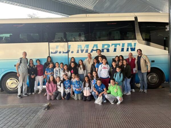 Grupo de alumnos de la Escuela Municipal de Baloncesto junto a un autobús