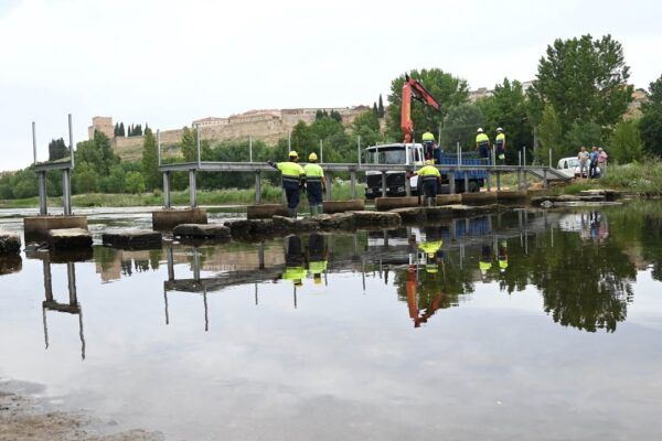 Trabajadores instalando una pasarela peatonal sobre el río Águeda