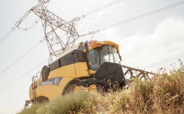 Cosechadora amarilla trabajando en un campo con electricidad