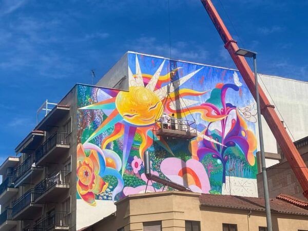 Mural colorido en el barrio del Oeste de Salamanca con un sol y flores
