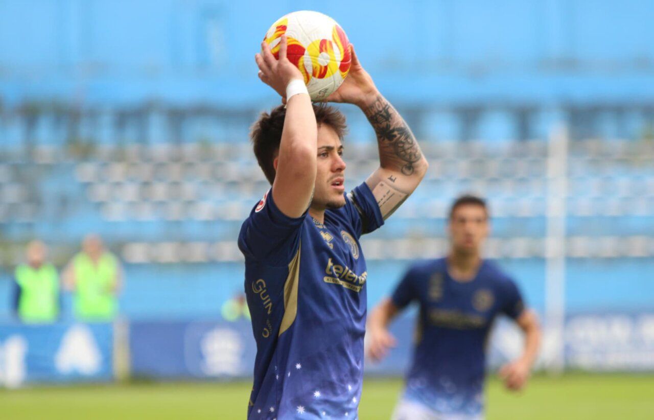 Jugador del Avilés lanzando el balón durante un partido de fútbol