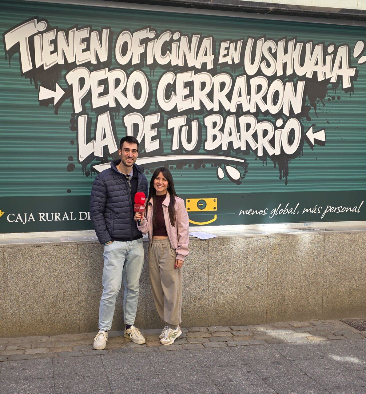 Dos personas frente a un mural de Caja Rural de Salamanca