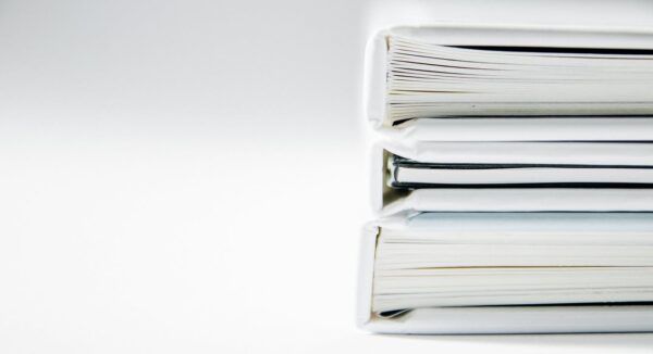 Tres carpetas apiladas con documentos en un fondo blanco