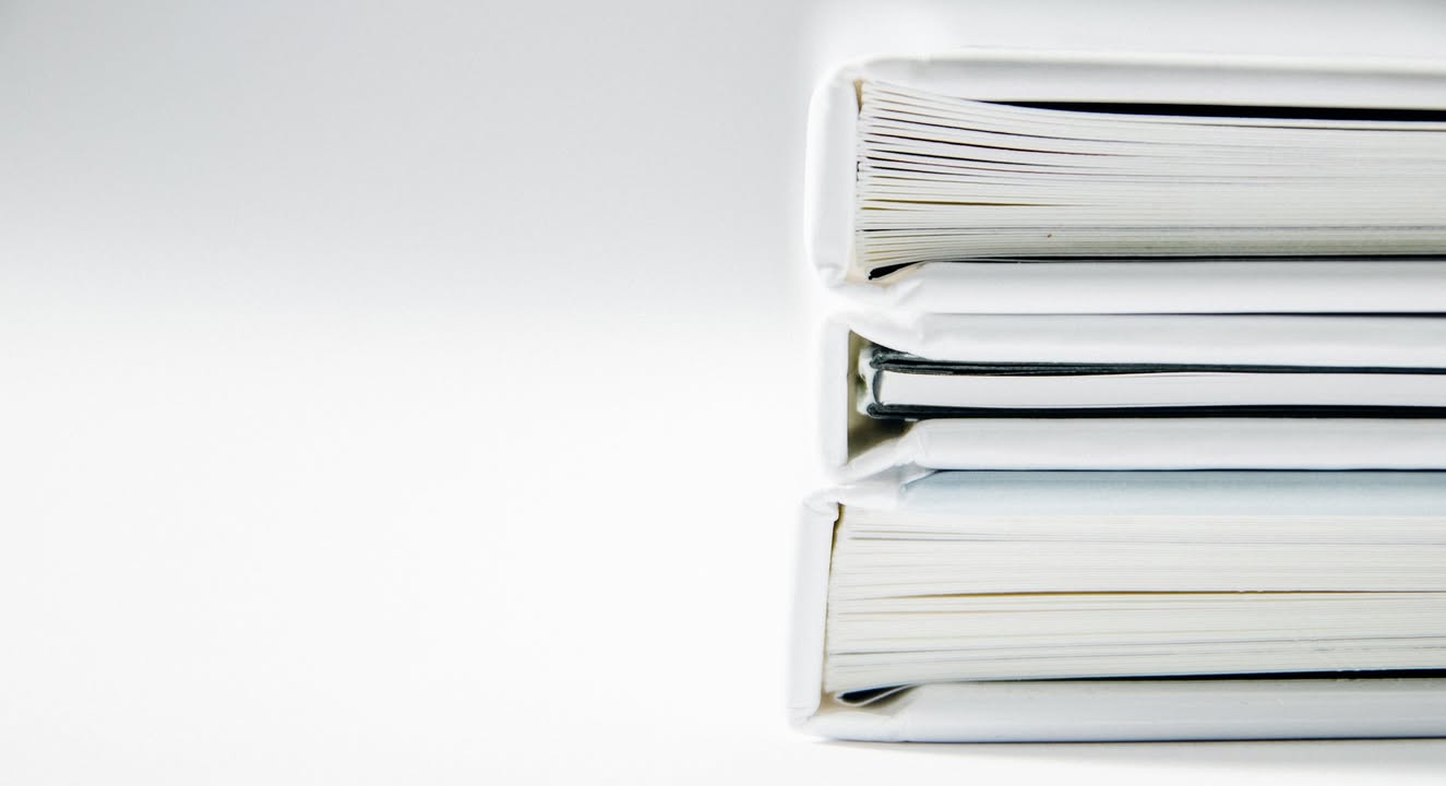 Tres carpetas apiladas con documentos en un fondo blanco