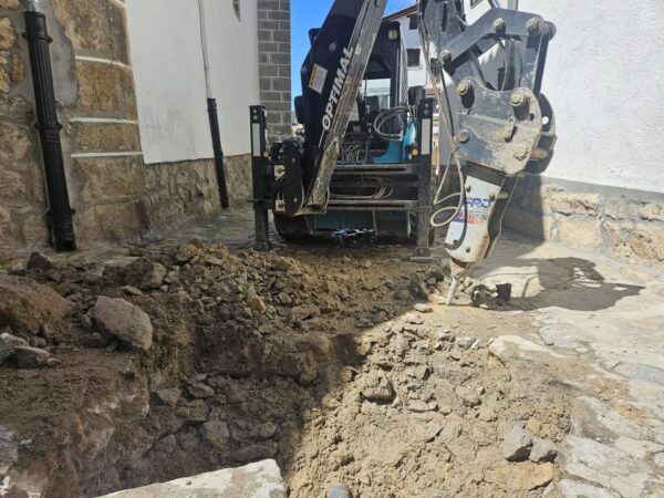 Excavadora trabajando en una calle con tubería rota