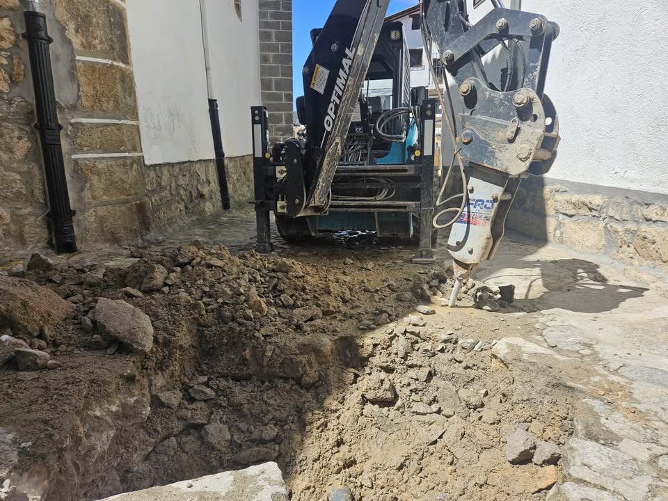 Excavadora trabajando en una calle con tubería rota