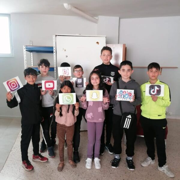 Grupo de niños sosteniendo carteles de redes sociales en un taller educativo