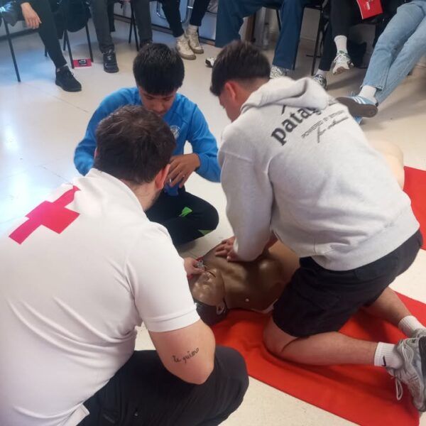 Estudiantes aprendiendo primeros auxilios con un maniquí en un curso de Cruz Roja