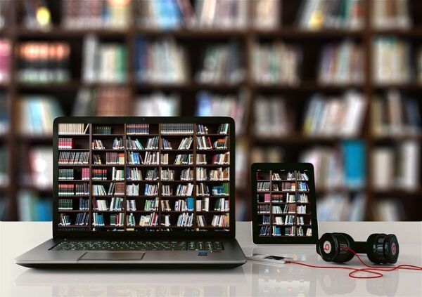 Computadora y tablet mostrando estanterías de libros en un entorno educativo.