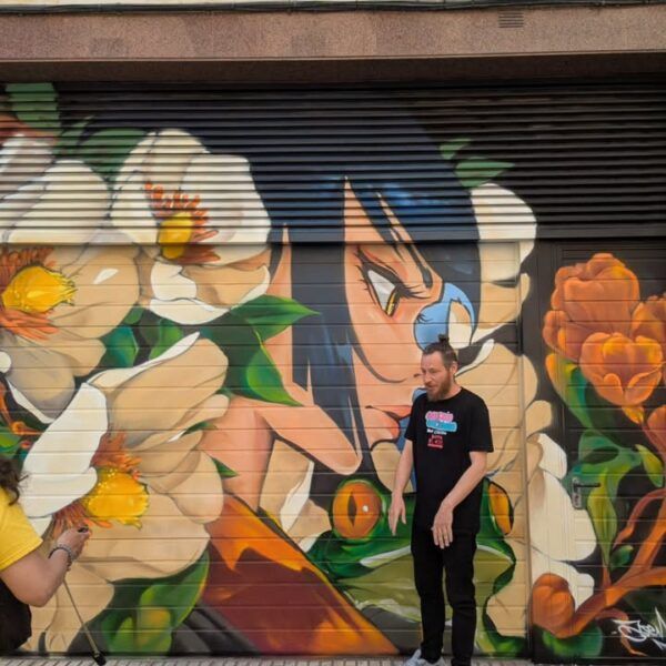 Artista junto a mural en la Galería Urbana Barrio del Oeste