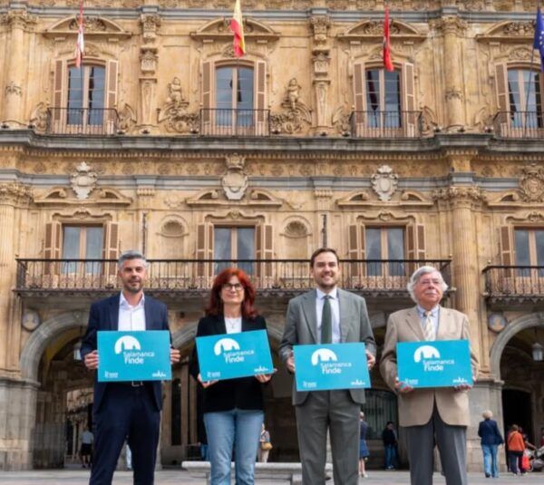 Cuatro personas sosteniendo carteles de Salamanca Finde frente a un edificio histórico