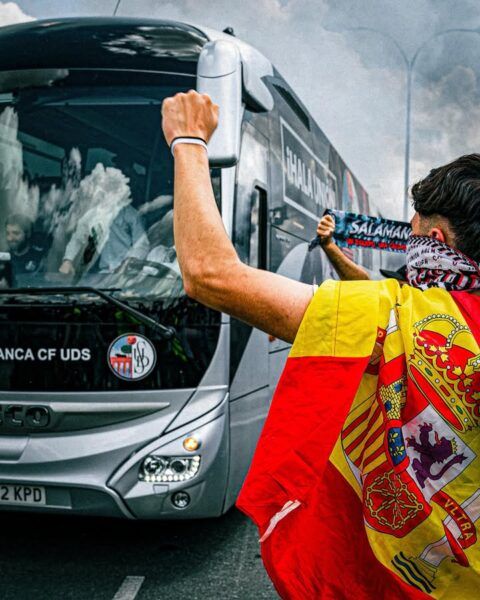 Aficionados animando a su equipo frente a un autobús