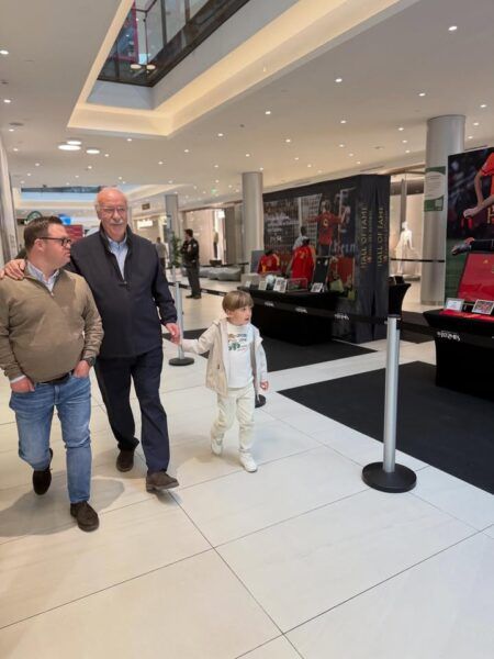 Vicente del Bosque caminando con un niño y un adulto en un evento