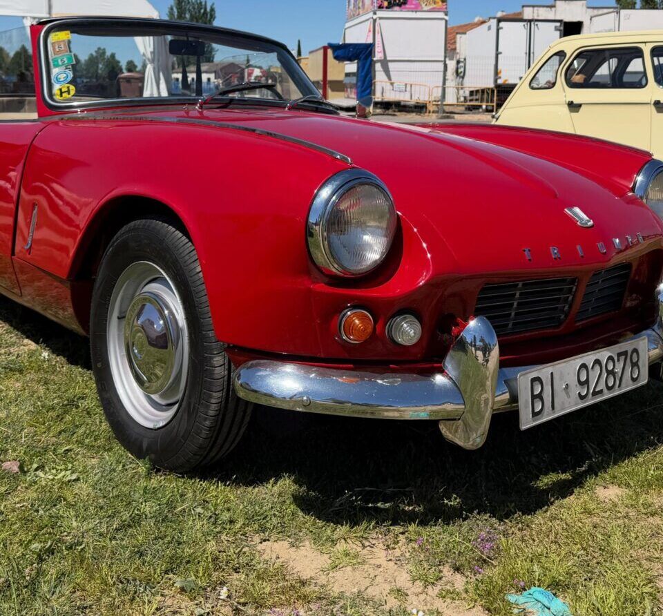 Coche rojo Triumph en las fiestas de Villamayor con ambiente festivo