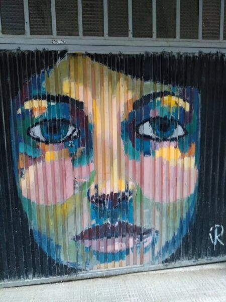 Mural colorido de un rostro en una puerta del barrio del Oeste en Salamanca