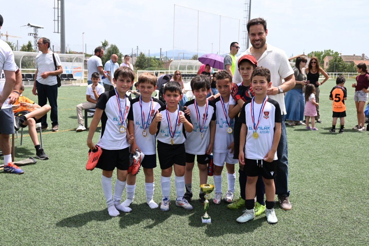 Niños posando con medallas y trofeo en campos de Toñete