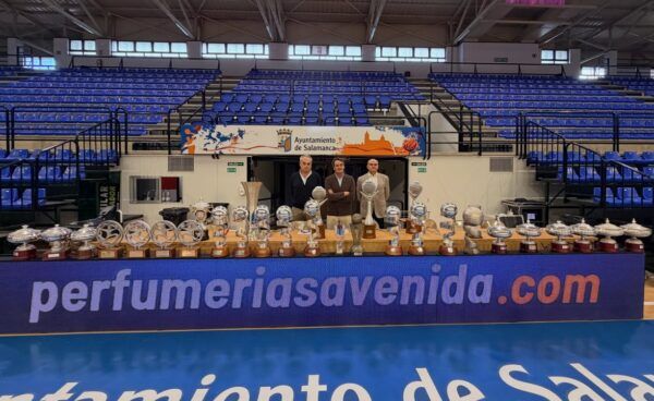 Tres hombres posando frente a una mesa con trofeos en un evento en Salamanca