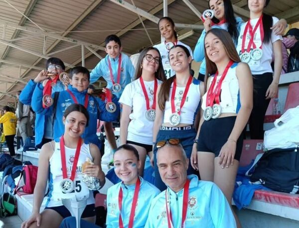 Grupo de atletas de la Escuela Municipal de Atletismo con medallas en el podio
