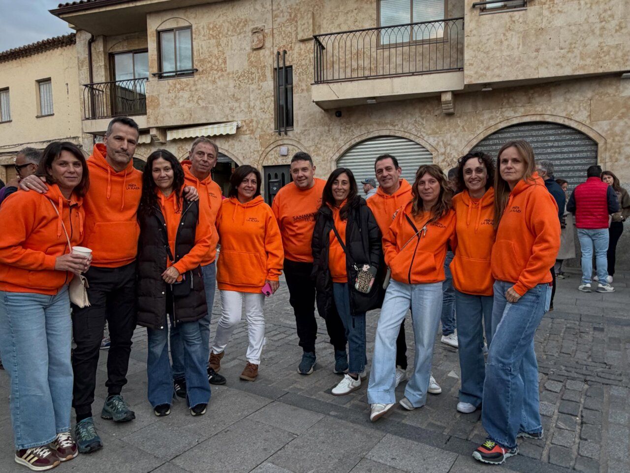 Grupo de personas con sudaderas naranjas en la fiesta de Villamayor