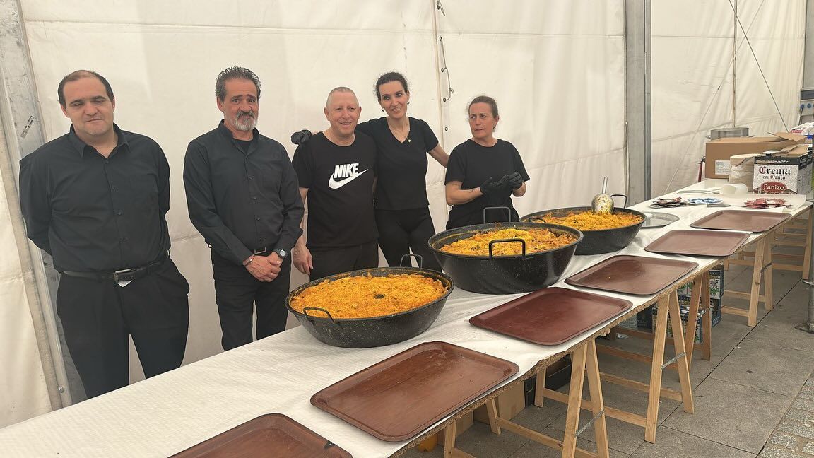 Personas en la fiesta de Villamayor preparando comida en grandes paelleras