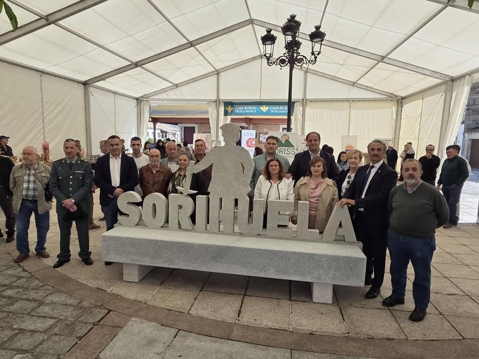 Grupo de personas en la II Feria de Artesanía de Sorihuela con un cartel de piedra