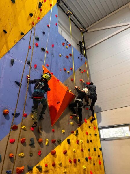 Niños escalando en un rocódromo durante una jornada escolar