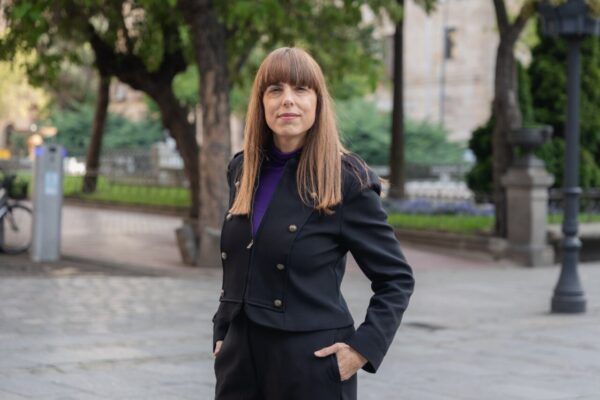 Mujer de pie en un parque con árboles y edificios al fondo