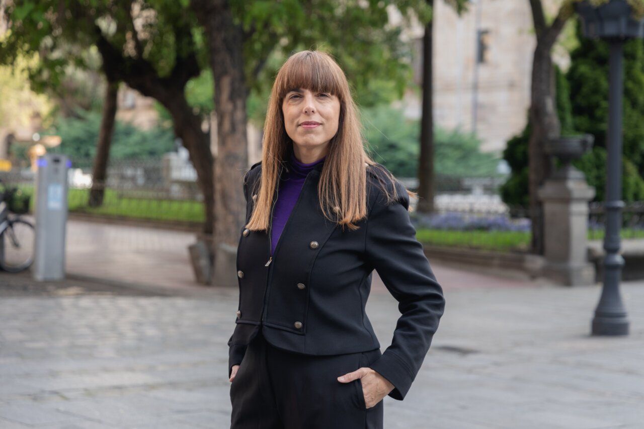 Mujer de pie en un parque con árboles y edificios al fondo