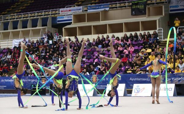 Gimnastas realizando una rutina con cintas en un evento deportivo