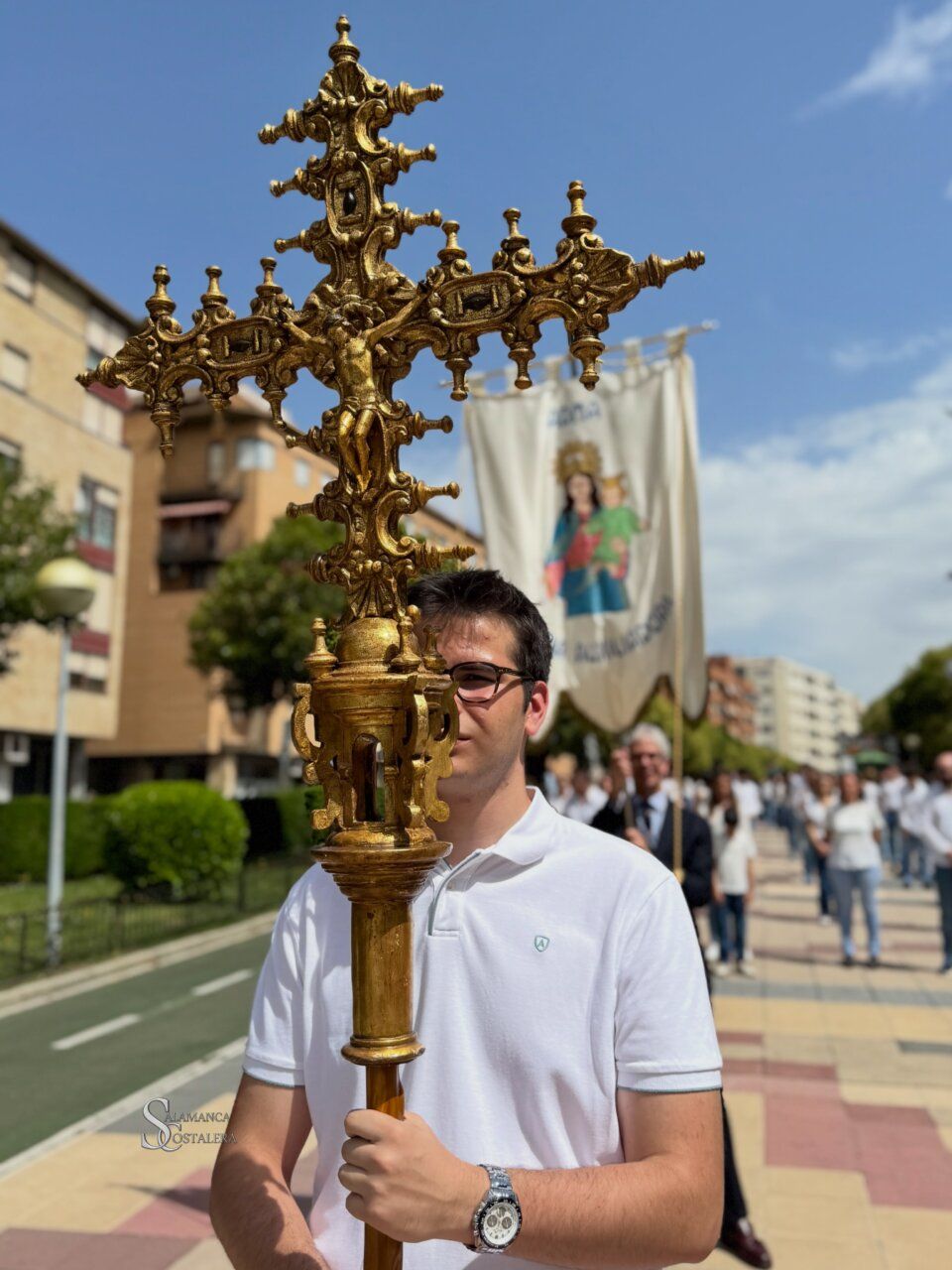 Joven sosteniendo una cruz dorada en la procesión de María Auxiliadora.