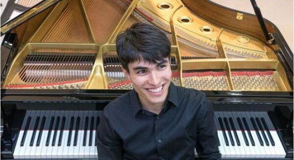 Miguel Vicente Brozas sonriente junto a un piano en el recital de piano
