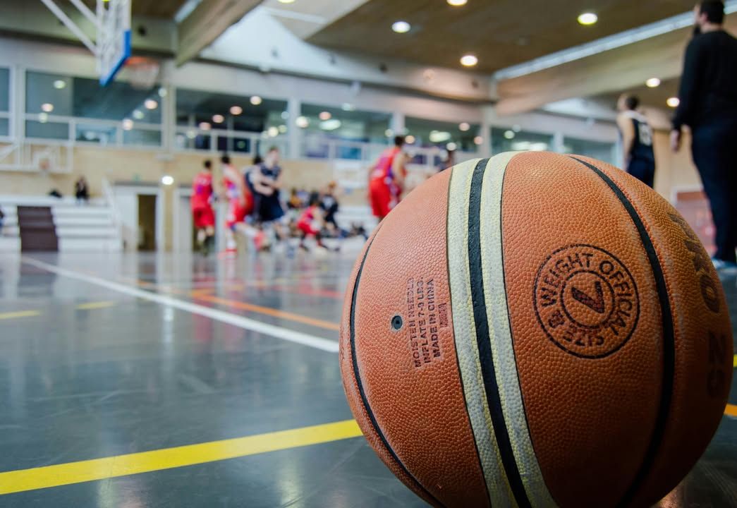 Balón de baloncesto en una cancha con jugadores en acción